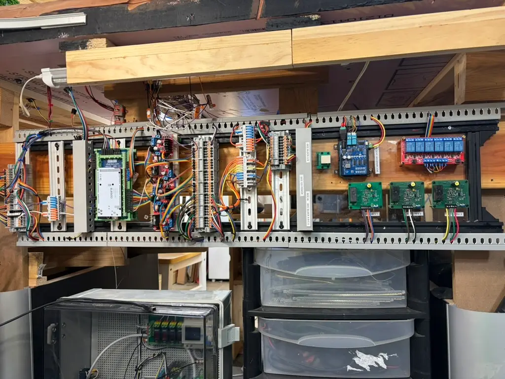 A Digital Dispatcher on the workbench: DIN rails of labeled terminals, an EX-CommandStation, servo drivers and relay boards in one aluminium frame